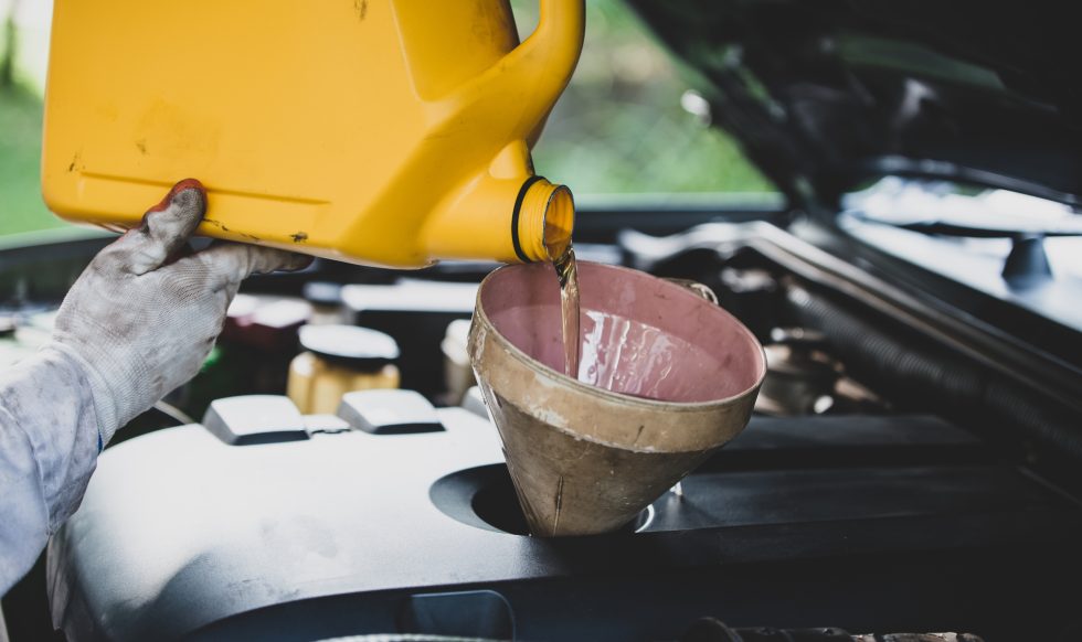 Close up Auto mechanic hand pouring and replacing fresh oil into car engine at auto repair garage. Automobile maintenance and industry concept